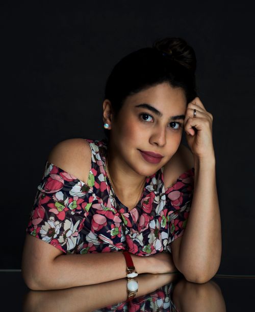 Free A smiling woman in a floral top leaning on a reflective surface with a dark background. Stock Photo
