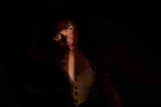 A captivating portrait of a woman highlighted by a dramatic light beam, creating a mysterious and moody atmosphere.