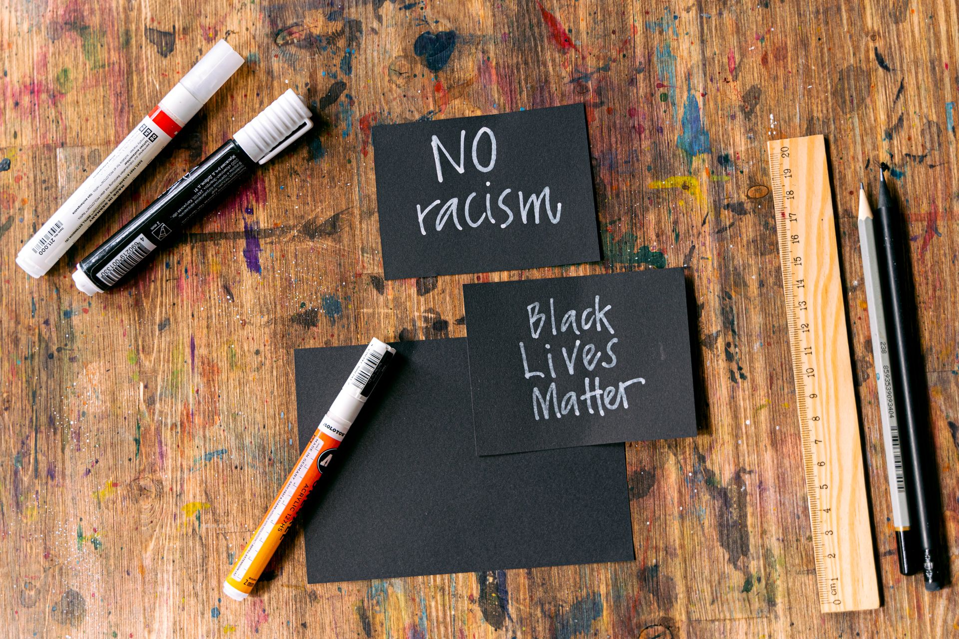 Creative activism cards with 'No Racism' and 'Black Lives Matter' messages on a rustic workbench.