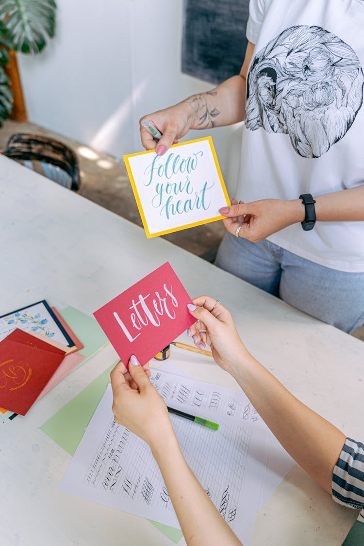 People Holding Cards With Handwritten Lettering