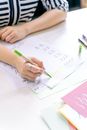 特写：一名妇女在室内用绿色记号笔在纸上练习书写字母
