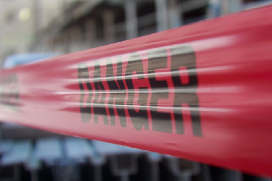 Red warning sign with caution symbol against dark background