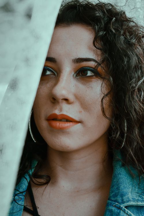 Free Young confident female with bright makeup and red lips in denim modern jacket looking away Stock Photo