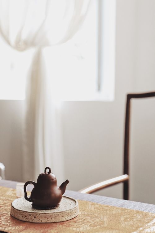 Free An elegant clay teapot sits on a sunlit table, exuding warmth and tranquility. Stock Photo