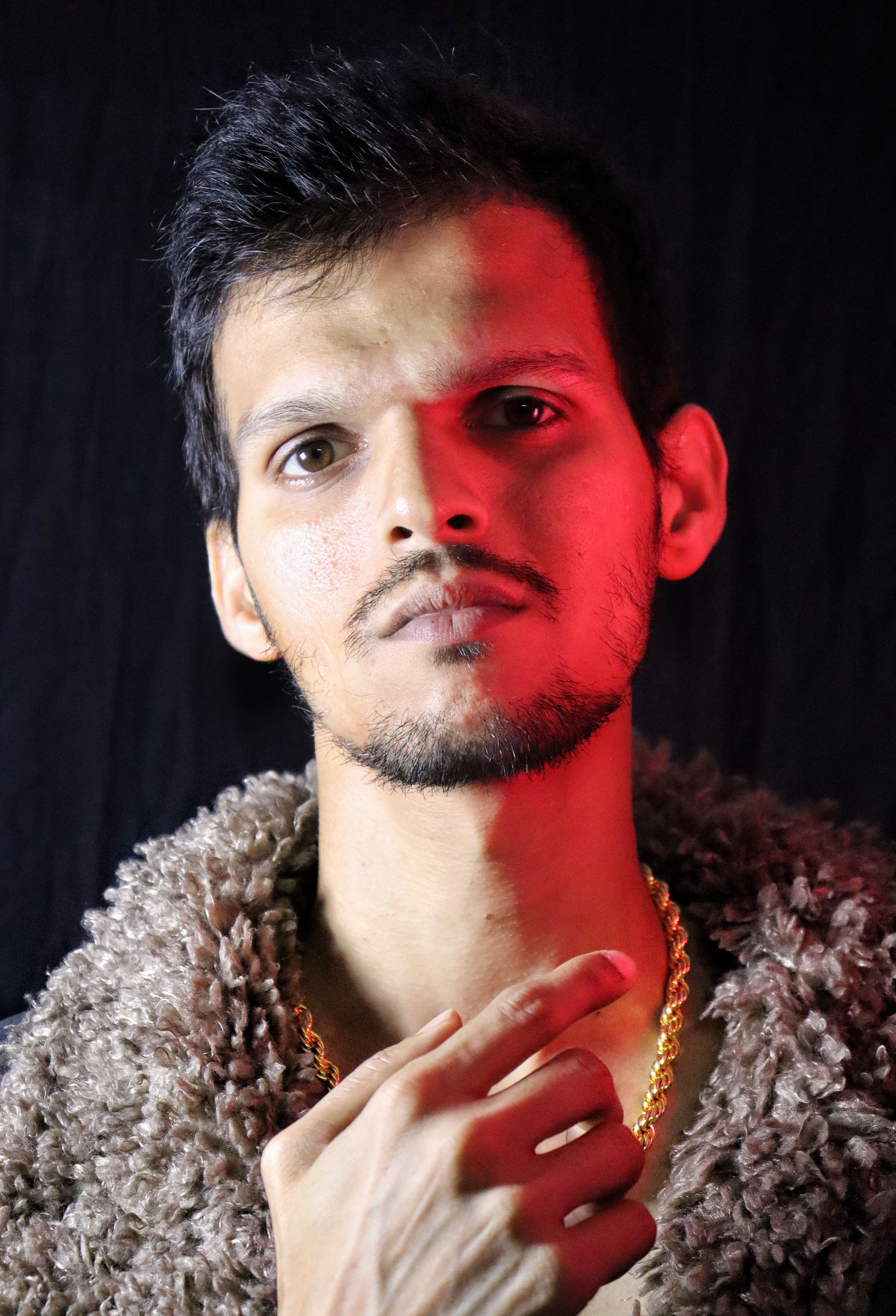 Studio portrait of a fashionable man in fur with red dramatic lighting.