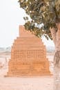 Historic tomb with carved patterns placed behind tree