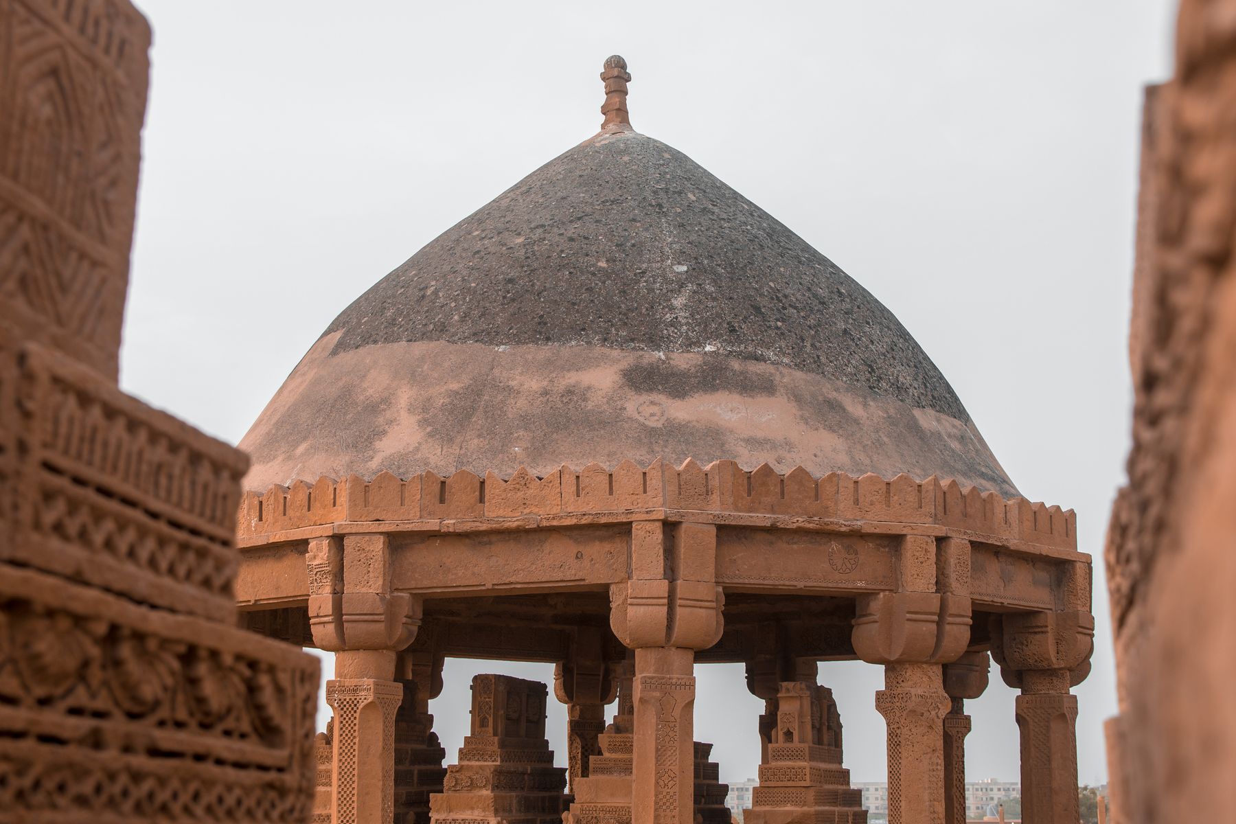 Ancient pyramid shaped tombs located under roof of mausoleum with sandstone columns located in Chaukhandi complex in Pakistan
