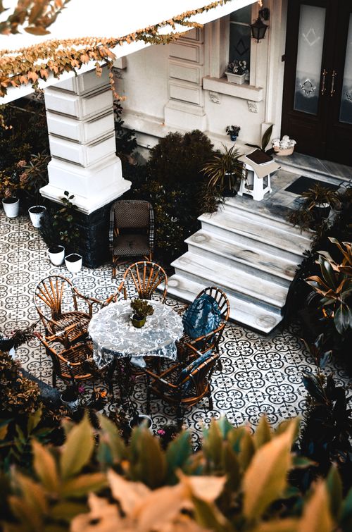 Free From above of terrace with potted plants and cozy round table with wooden chairs located near stylish house in daytime Stock Photo