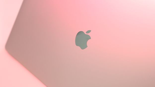 Close-up image of a sleek laptop on a soft pink background, creating a modern and minimalist aesthetic.