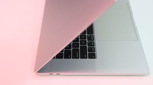 Free Modern laptop partially closed with a soft pink hue, perfect for tech-themed projects. Stock Photo