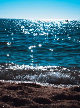 Amazing scenery of bright blue seawater washing sandy coast and reflecting bright sunshine under blue sky