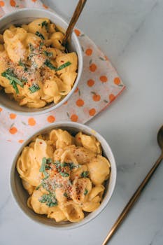 Delicious creamy vegan mac and cheese topped with herbs, served in bowls.