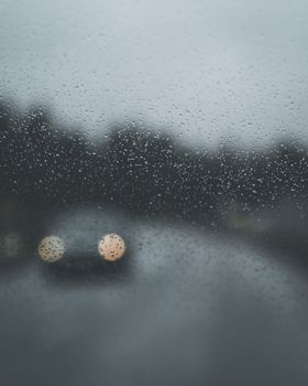 透过雨点覆盖的窗户，波兰街道上忧郁的景色和模糊的汽车映入眼帘