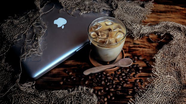 A refreshing iced coffee with laptop on a rustic table, perfect for work breaks.