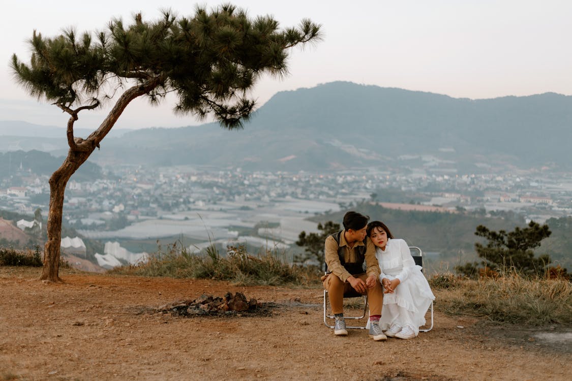 Full body of Asian couple sitting close to each other and enjoying romantic moment together