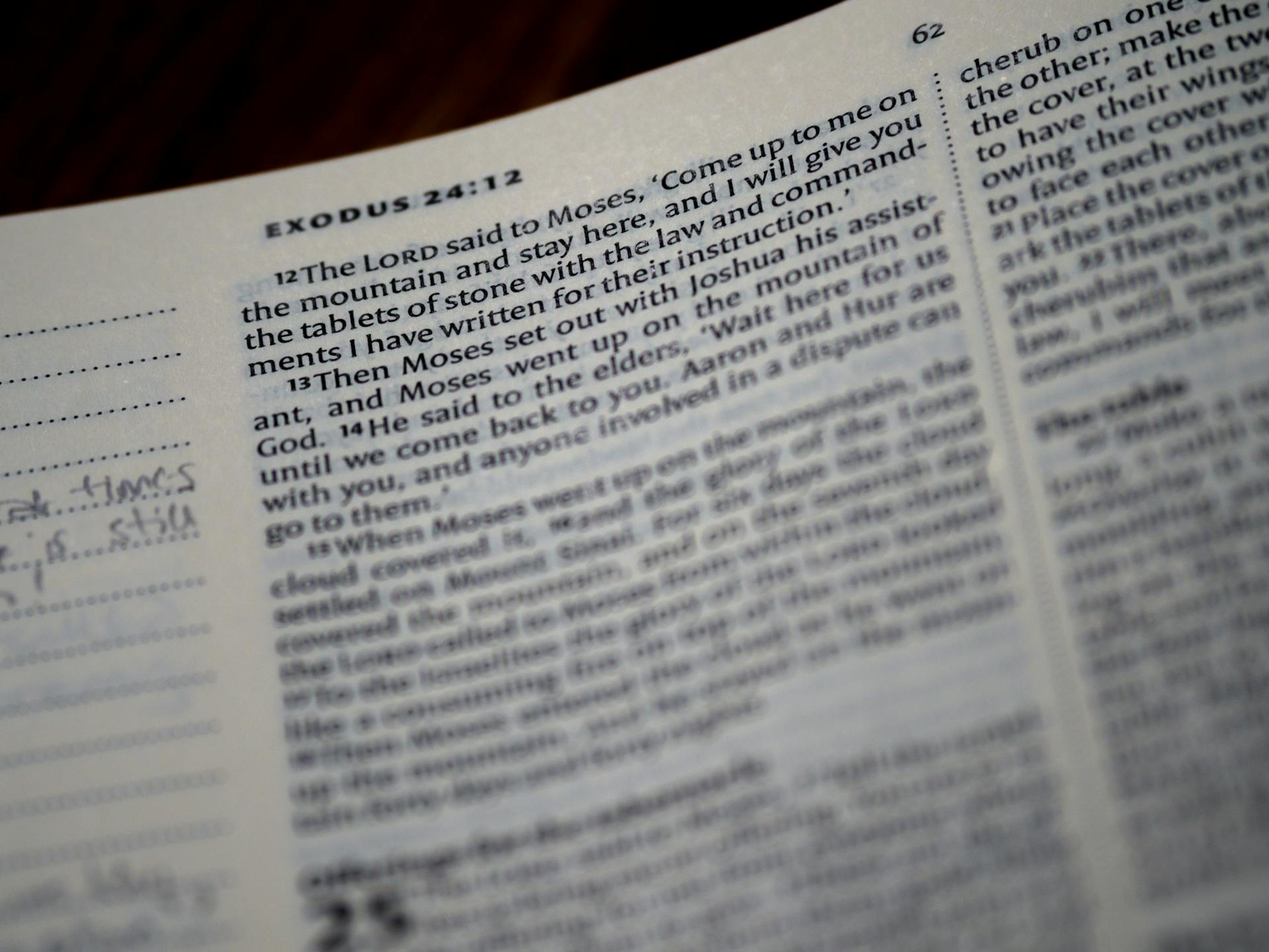 Close-up of an open Bible displaying text from Exodus 24:12.