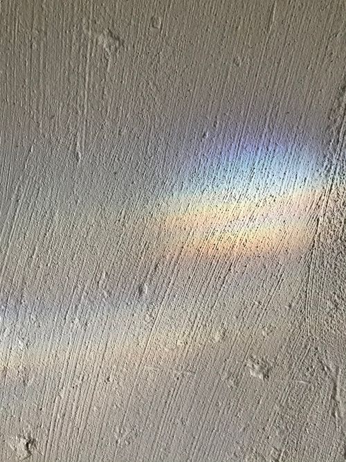 Free Close-up of a concrete wall with textured surface and a prism light reflection creating rainbow colors. Stock Photo