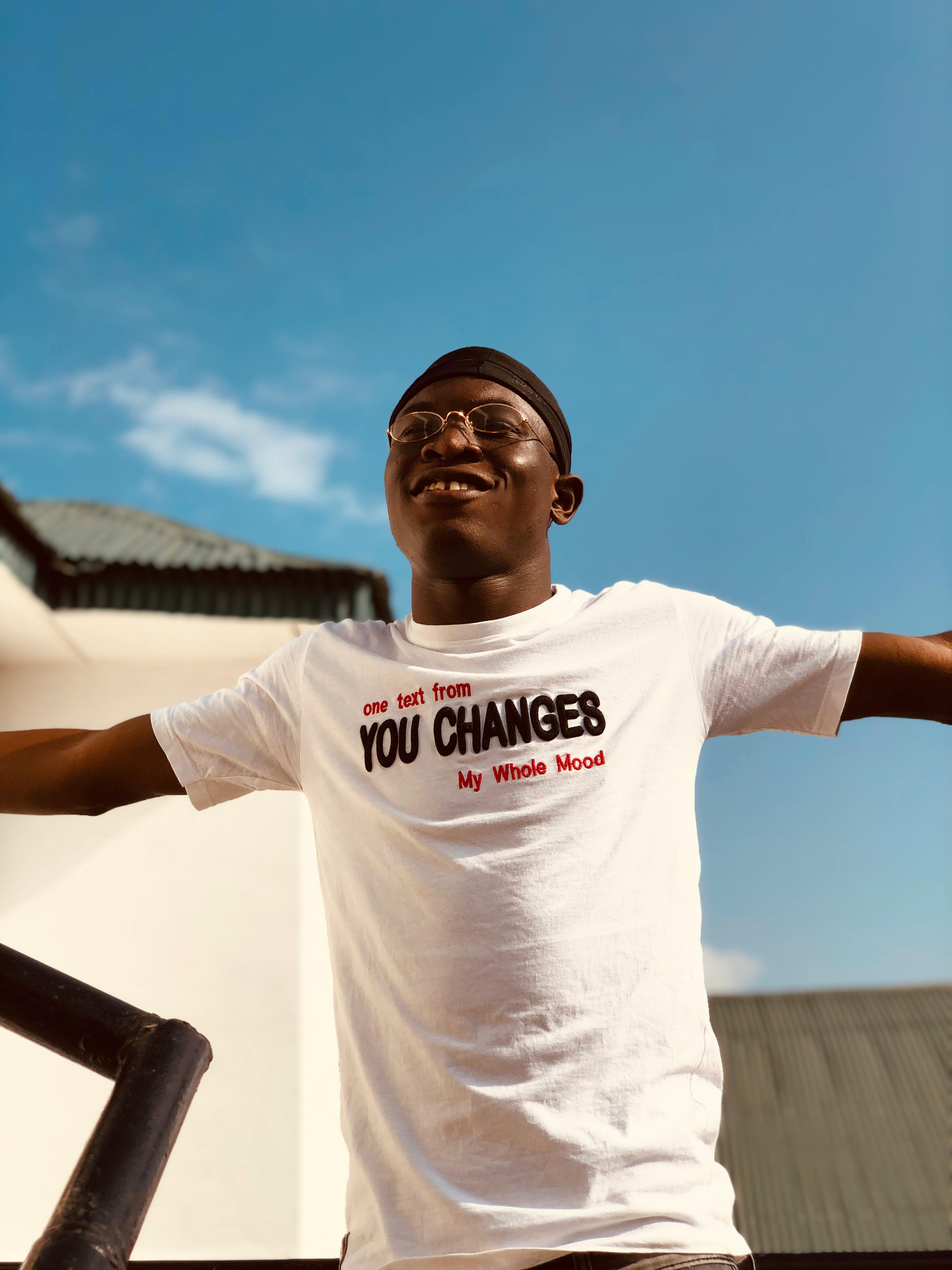Cheerful young man in a white shirt smiling under the blue sky in Ondo, Nigeria.