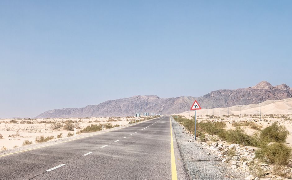 A car driving on a wide, well-maintained highway in Saudi Arabia with desert landscape.