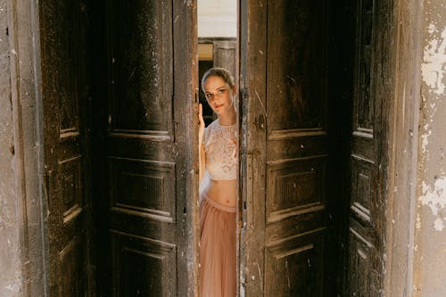 Free A Woman in Lace Top Standing Between the Wooden Door Stock Photo
