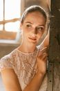 Woman in White Floral Lace Shirt Leaning on Brown Wooden Fence