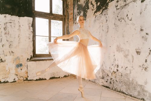 Free Ballerina gracefully posing on pointe in a rustic room. Stock Photo