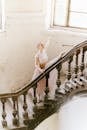 Woman in White Sleeveless Dress Standing on Staircase