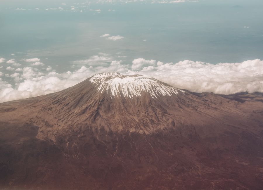 Breathtaking aerial view of Mount Kilimanjaro's snow-capped peak surrounded by clouds.