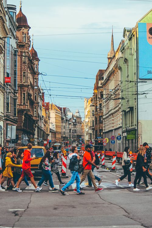 Free People walking along crosswalk in old district of city with historic local buildings Stock Photo