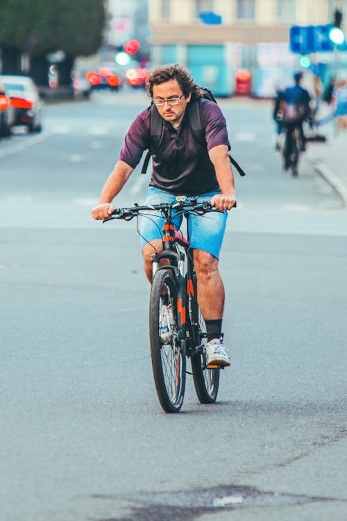 Man Wearing Purple Polo Shirt Riding a Bicycle