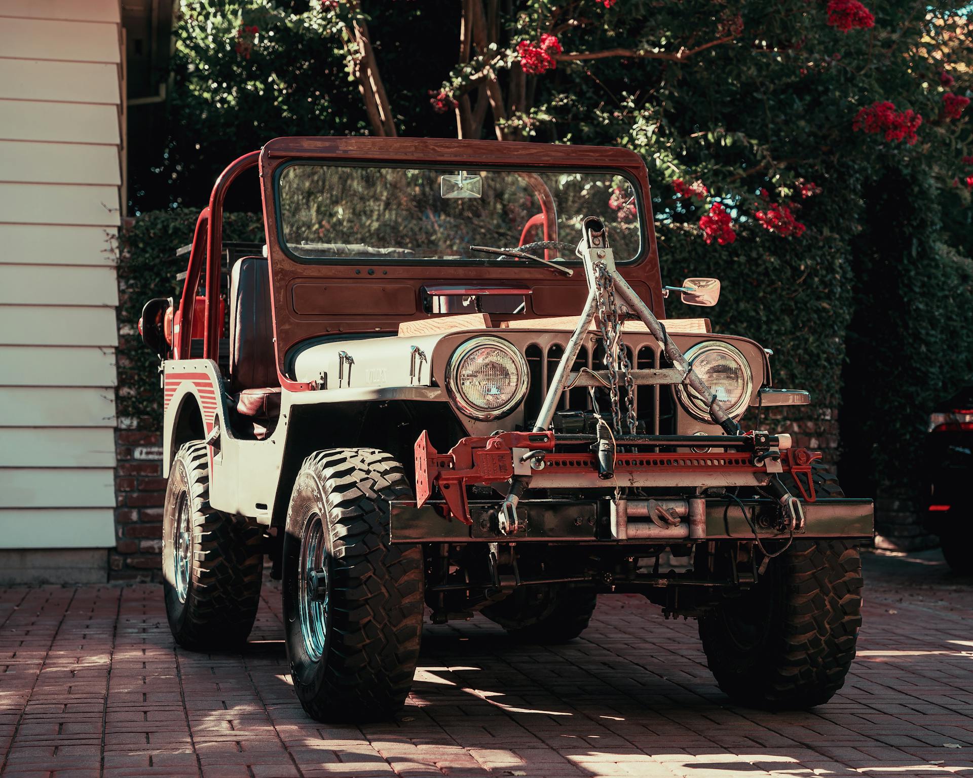 A classic 4x4 jeep with winch parked outdoors on a sunny day.