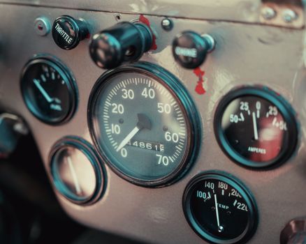 Close-up of a vintage car dashboard featuring a speedometer and various gauges.