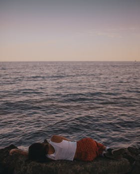 在一个宁静的夜晚，一名妇女在安大略湖平静的岩石岸边休息