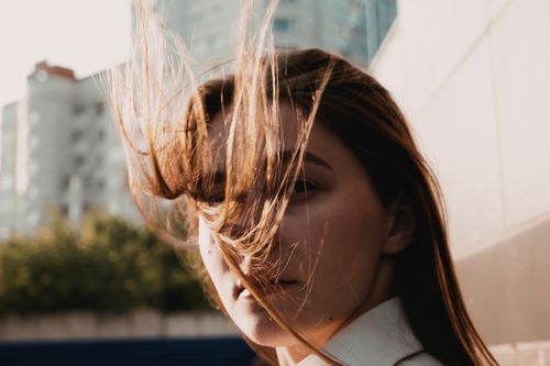 Free Portrait of a young woman outdoors with her hair blowing in the wind on a sunny day. Stock Photo