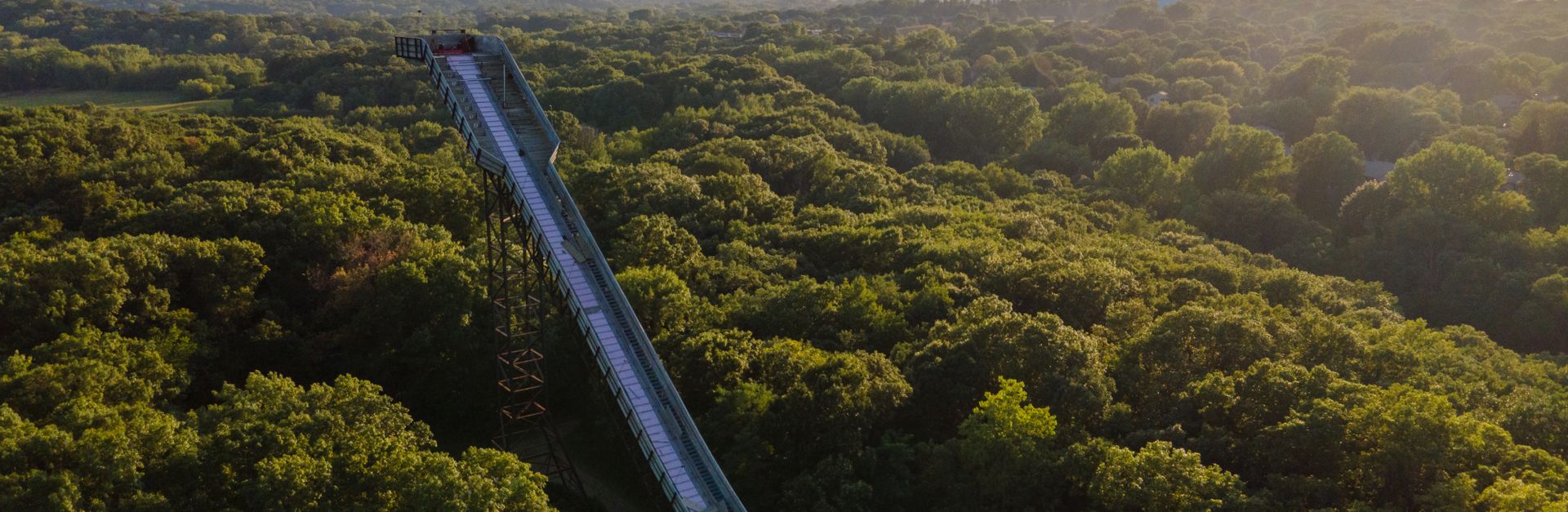 A panoramic aerial shot of a forest with a long water slide at sunset in Bloomington, Minnesota.