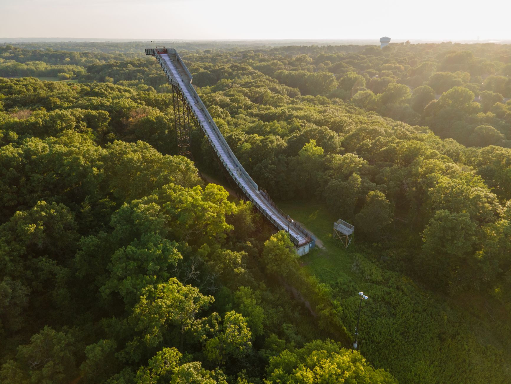 Aerial view of a slide surrounded by lush green forest in Bloomington, Minnesota during a sunny day.