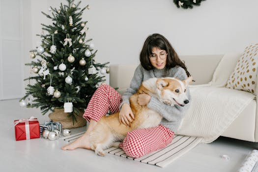 一位女士带着她的狗坐在圣诞树旁，享受着节日的气氛