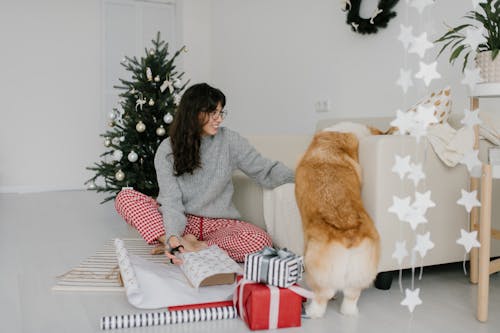 Smiling Woman wrapping a Gift with the Dog beside her