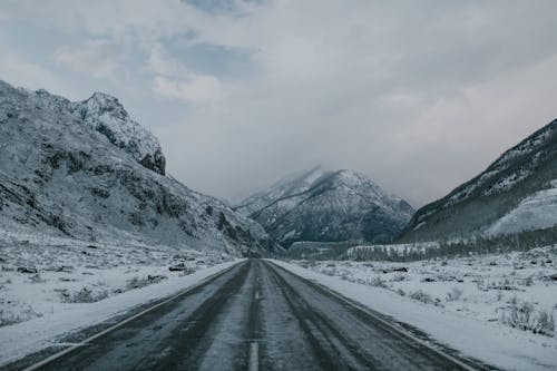 Asphalt road through snowy mountainous terrain