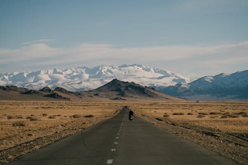 Snowy mountains behind asphalt road and hills