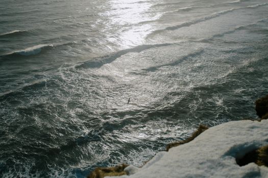 从空中俯瞰冰岛海岸线，海浪充满活力，悬崖白雪皑皑，景色令人惊叹