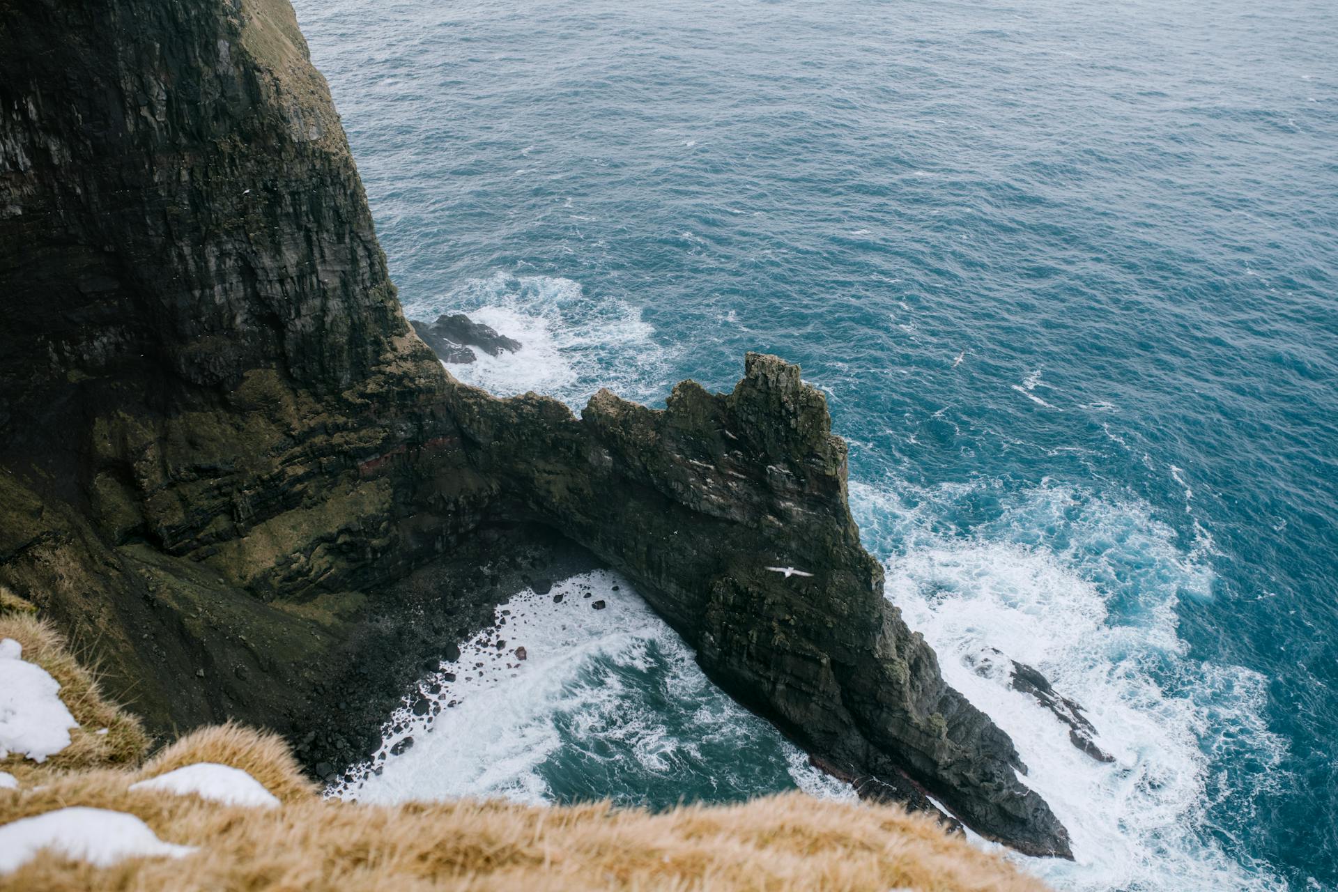 A breathtaking view of the Faroese cliffs with waves crashing against the rugged coastline.