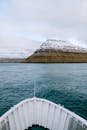 法罗群岛宁静的水域中，船头面向白雪皑皑的山脉