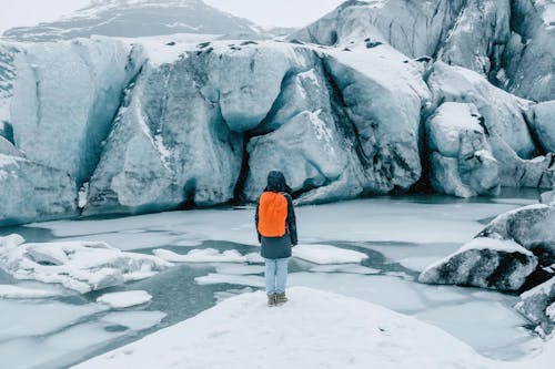 Person Standing on Ice near Glacier
