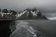 冰岛维斯特拉霍恩的海岸景色忧郁，白雪皑皑的山峰与漆黑的大海相映