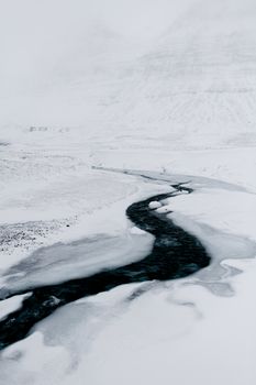 冰冻的溪流流经冰雪覆盖的冰岛地形，构成一幅宁静的冬季景观