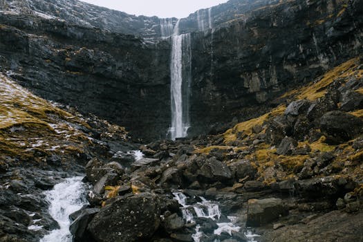 Stunning view of a waterfall cascading down rocky terrain in the scenic Faroe Islands.