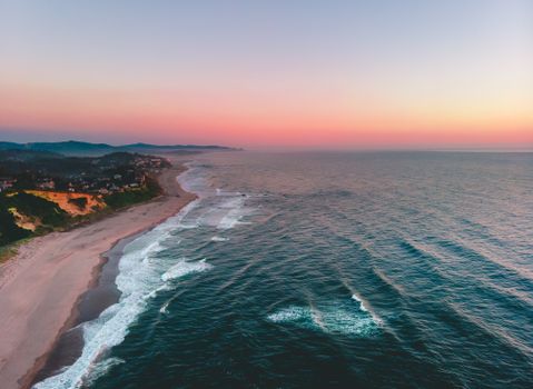 A breathtaking aerial view of Lincoln City's coastline during a vibrant sunset.