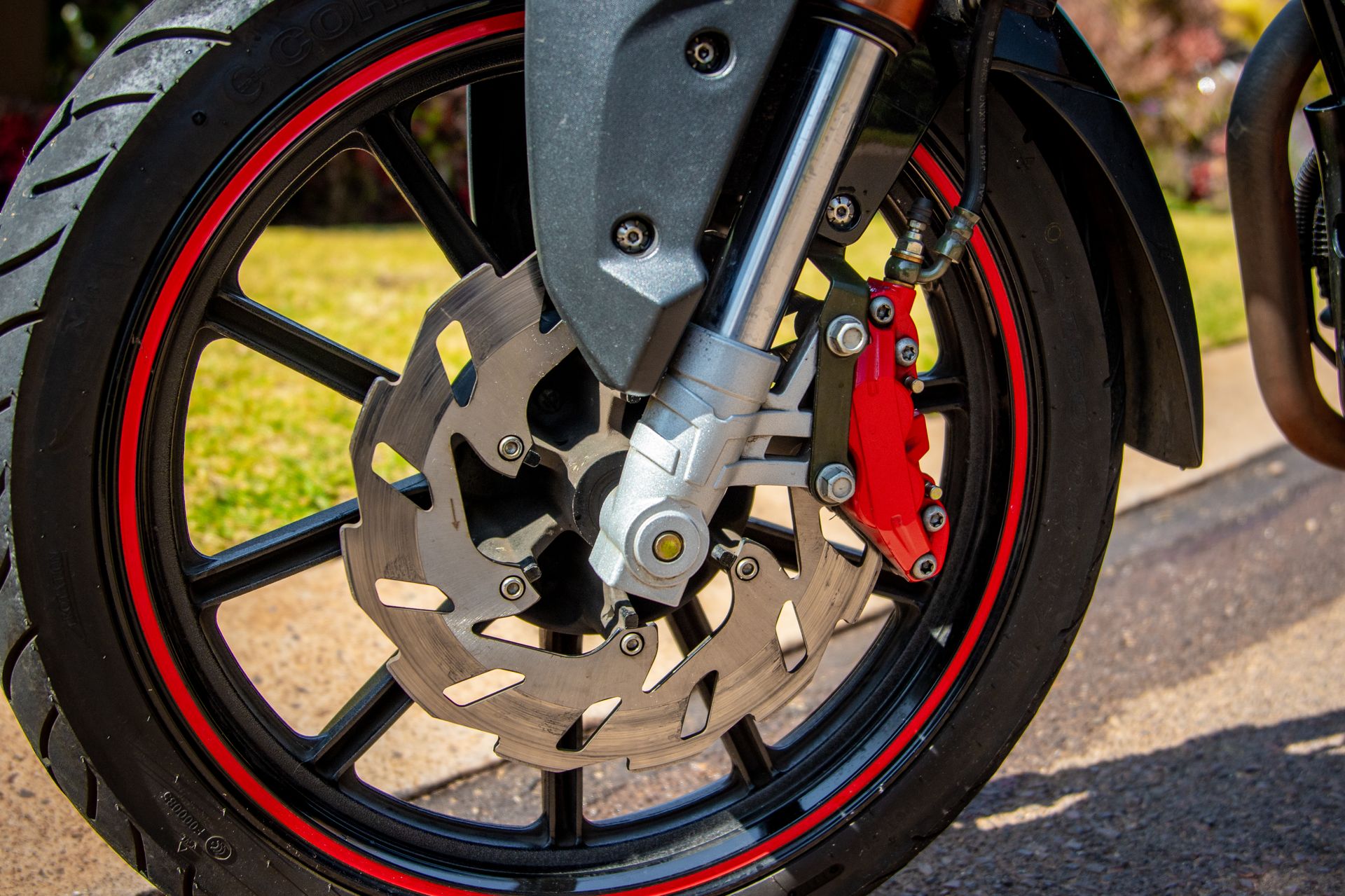 A close-up view of a modern motorcycle wheel featuring a disc brake and tire on a sunny day.