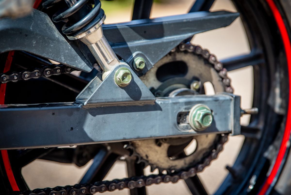 Close-up of motorcycle chain being inspected and lubricated during spring maintenance